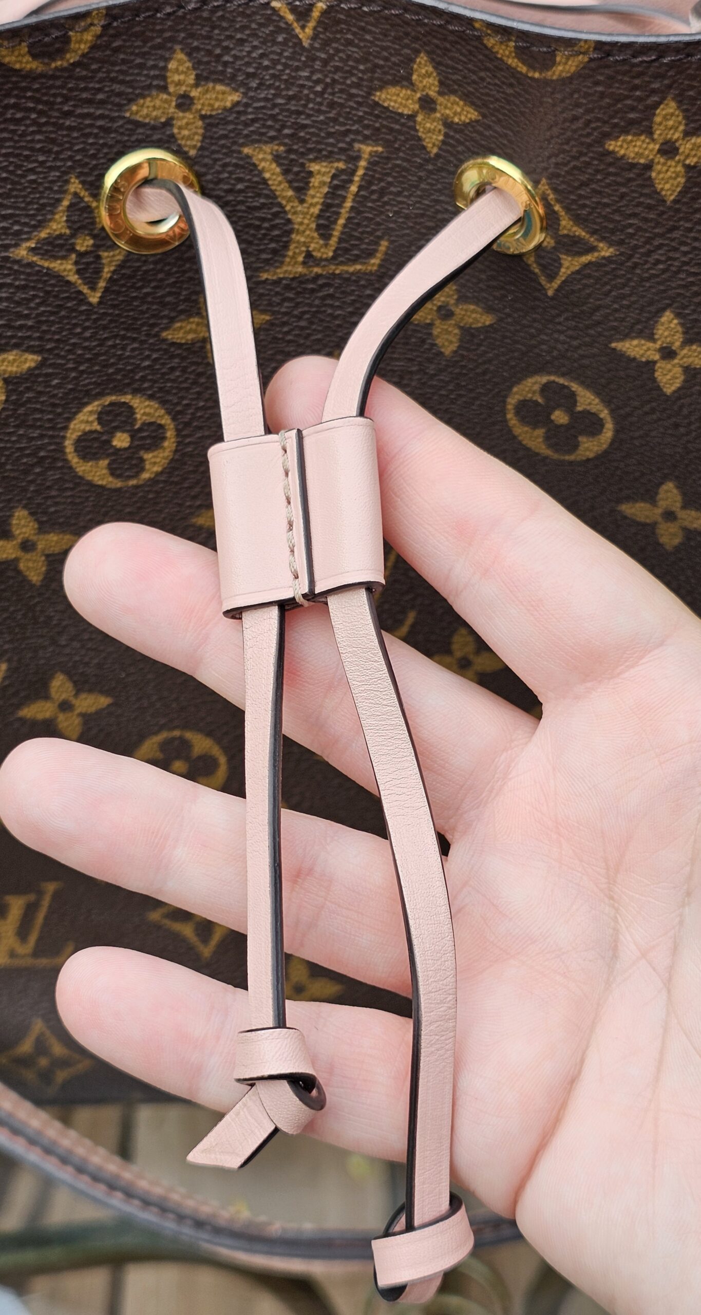 Rose Poudre leather drawstring cords of the Louis Vuitton Monogram NeoNoe MM held in hand