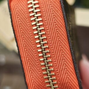 Gold-tone zip running around the Piment orange edge of the Louis Vuitton Zippy Multicartes