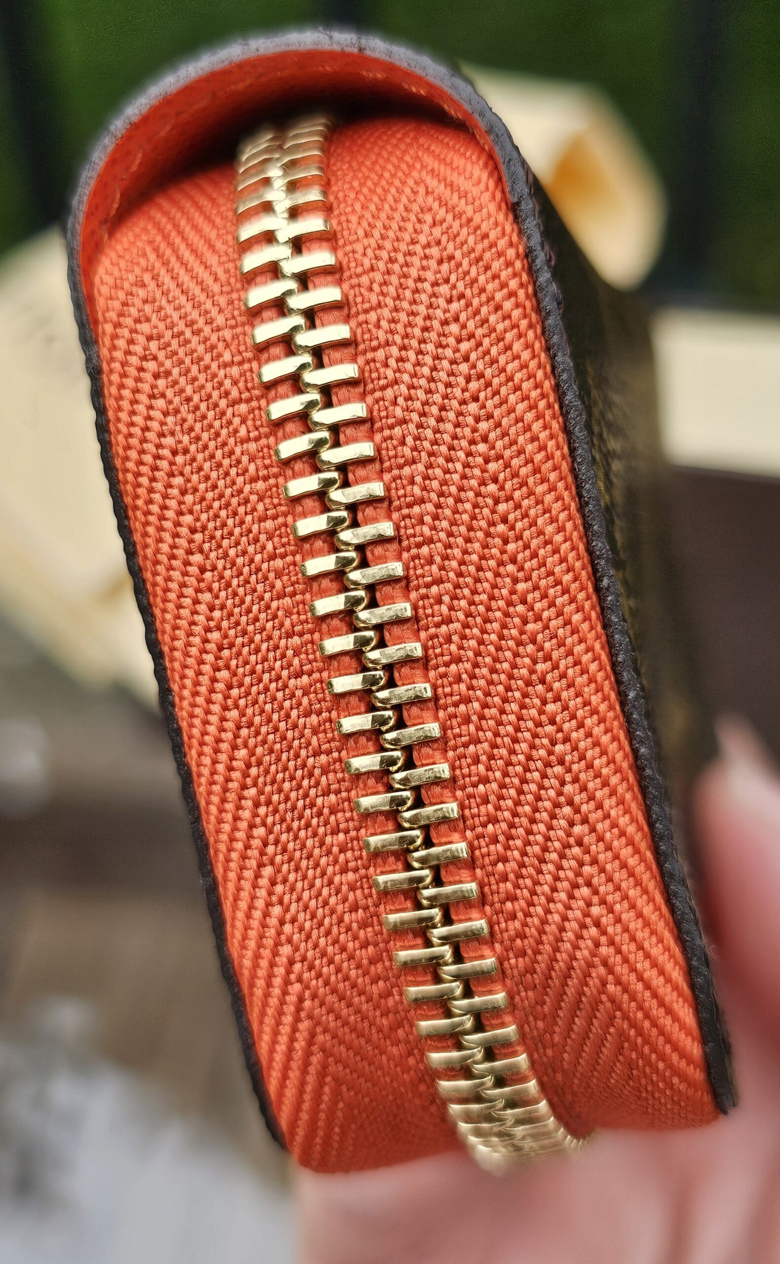Gold-tone zip running around the Piment orange edge of the Louis Vuitton Zippy Multicartes