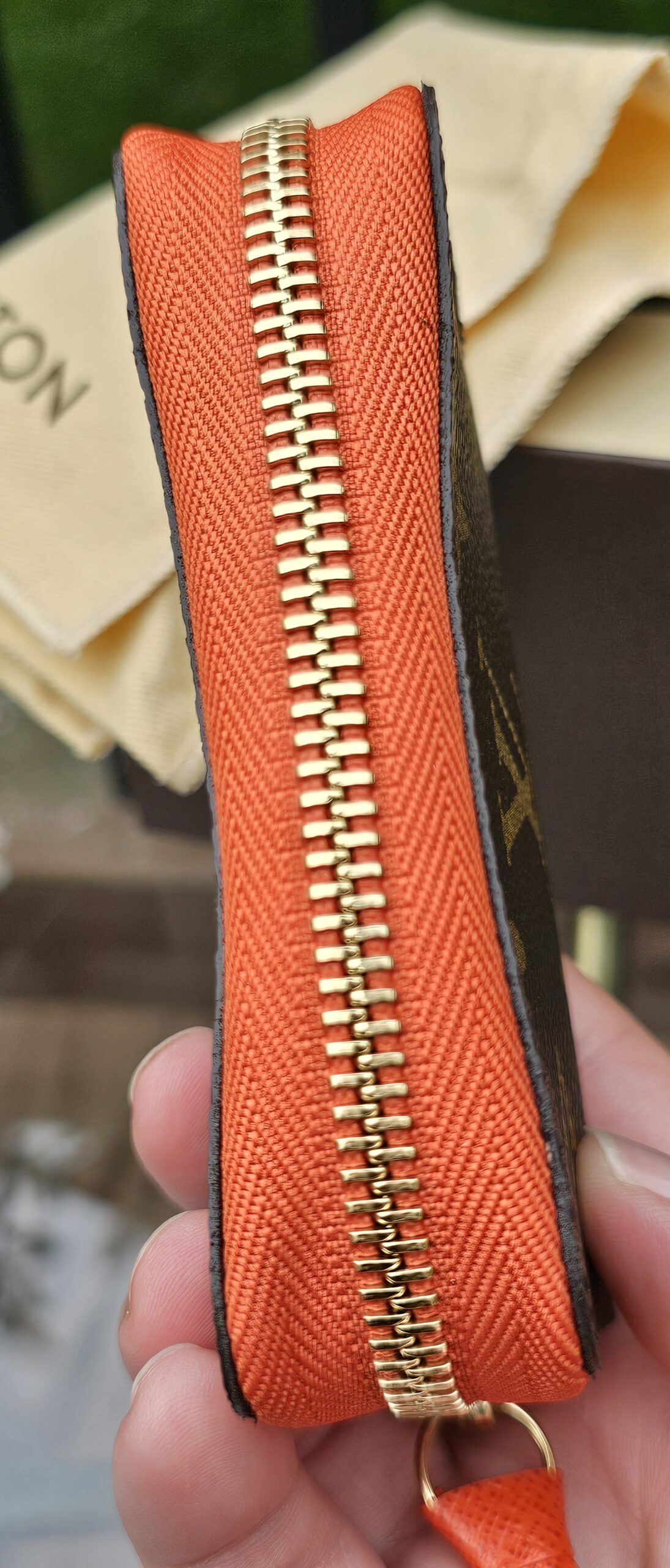 Side profile of the Louis Vuitton Zippy Multicartes showing the orange leather trim