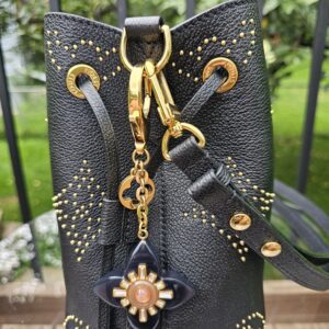 Louis Vuitton Fleur d Etoile charm hanging from a black studded handbag, shown for scale