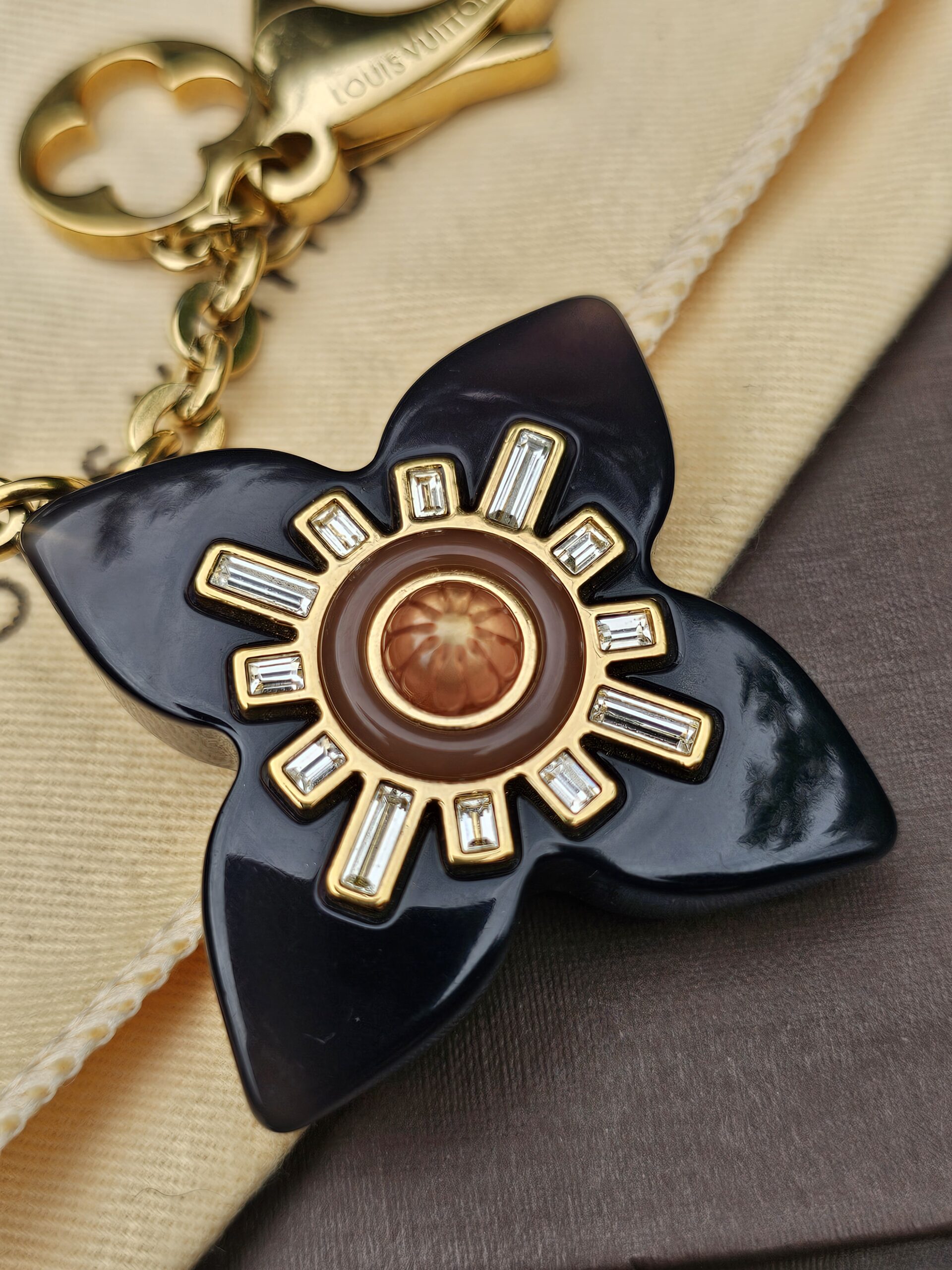 Black resin flower with crystal baguettes and a brown center on the Louis Vuitton Fleur d Etoile charm
