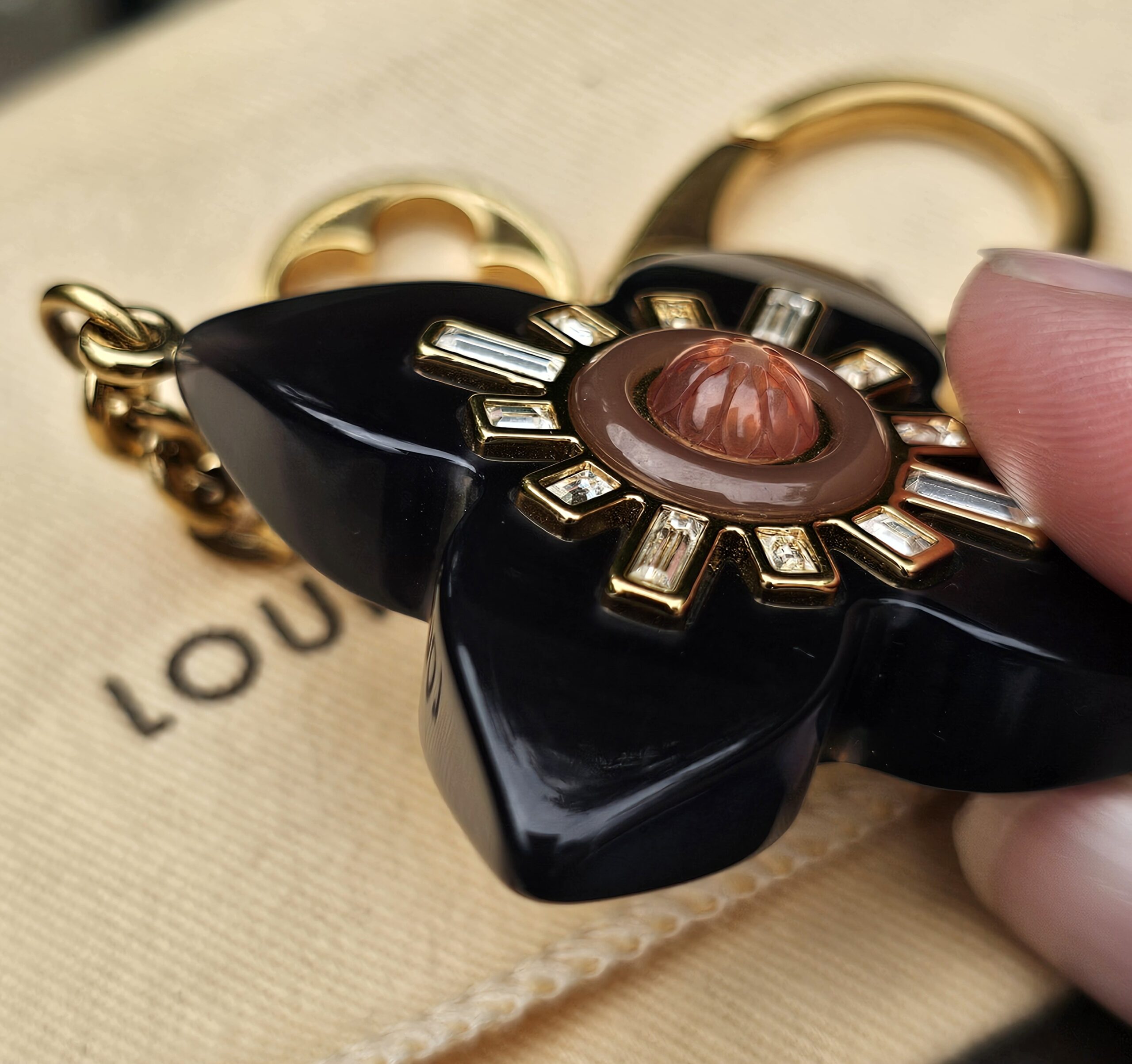Louis Vuitton Fleur d Etoile bag charm held in hand to show scale