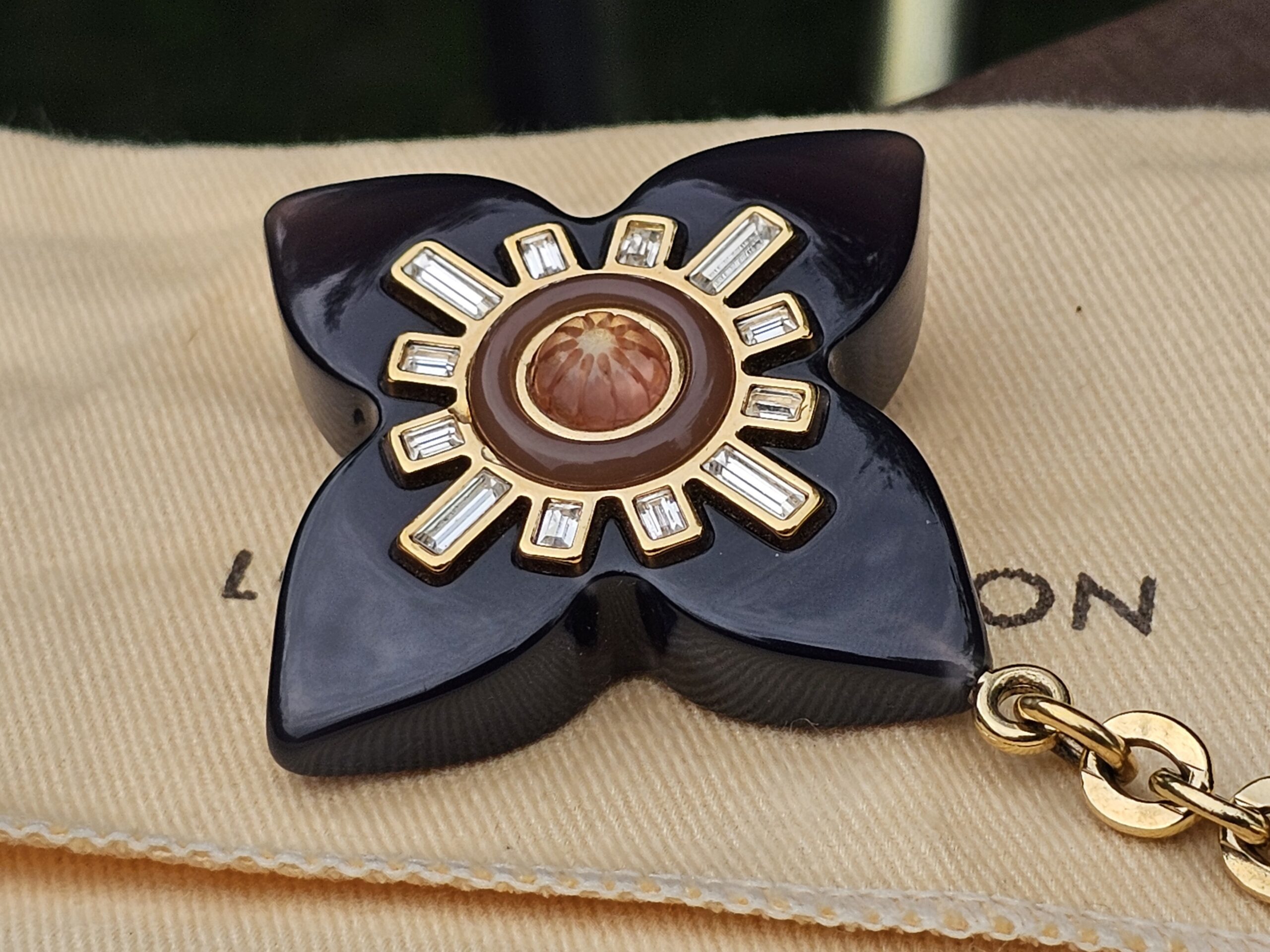 Louis Vuitton Fleur d Etoile charm resting on its Louis Vuitton dust bag