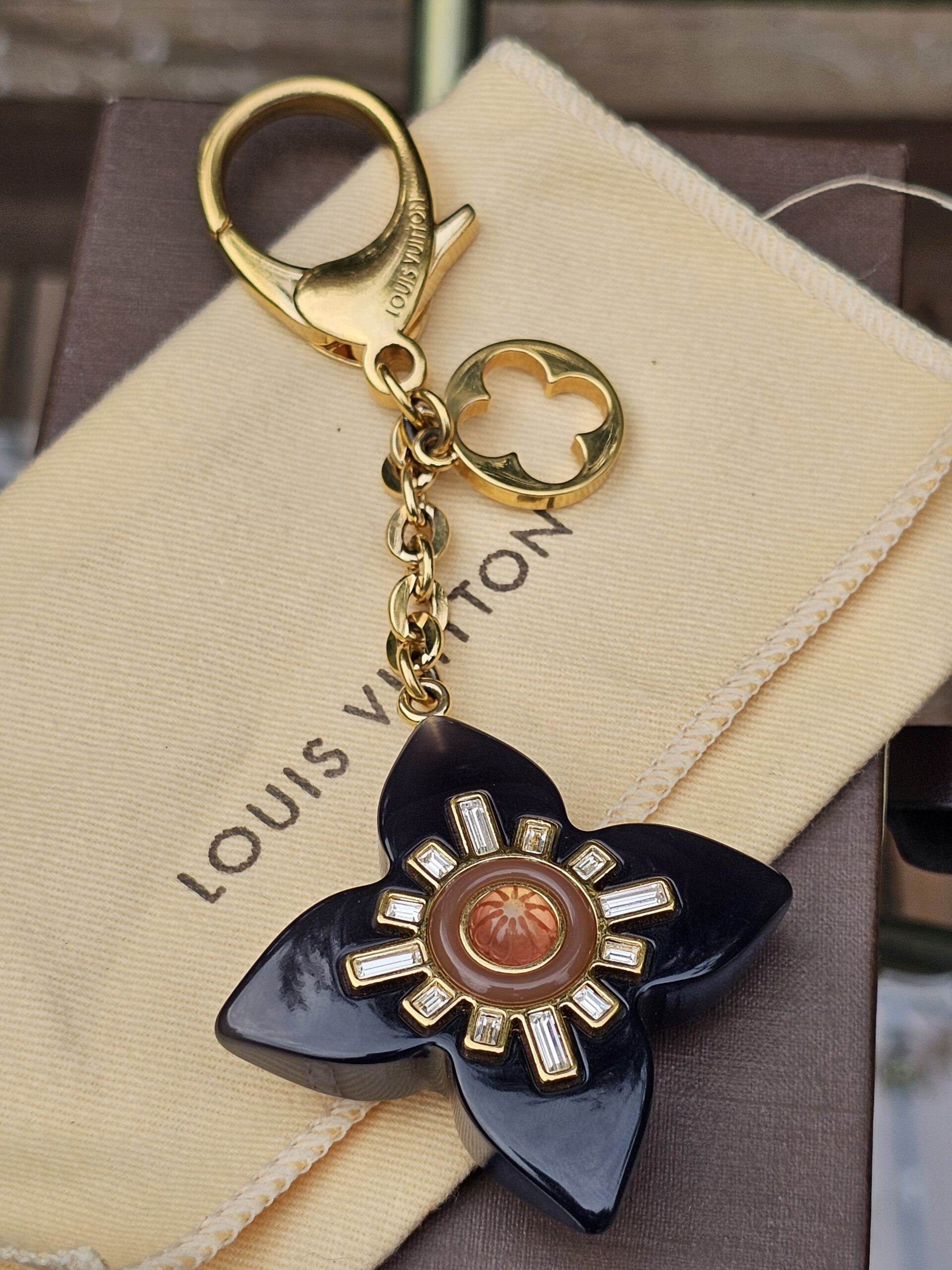 Full view of the Louis Vuitton Fleur d Etoile key holder and bag charm with chain and clasp