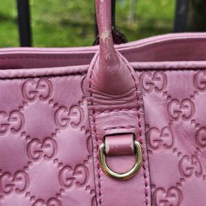 Base of the leather handle where it meets the pink Guccissima tote body
