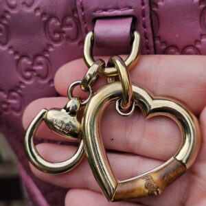 Gucci Heart Bit charm with bamboo accent held in hand, showing wear to the bamboo