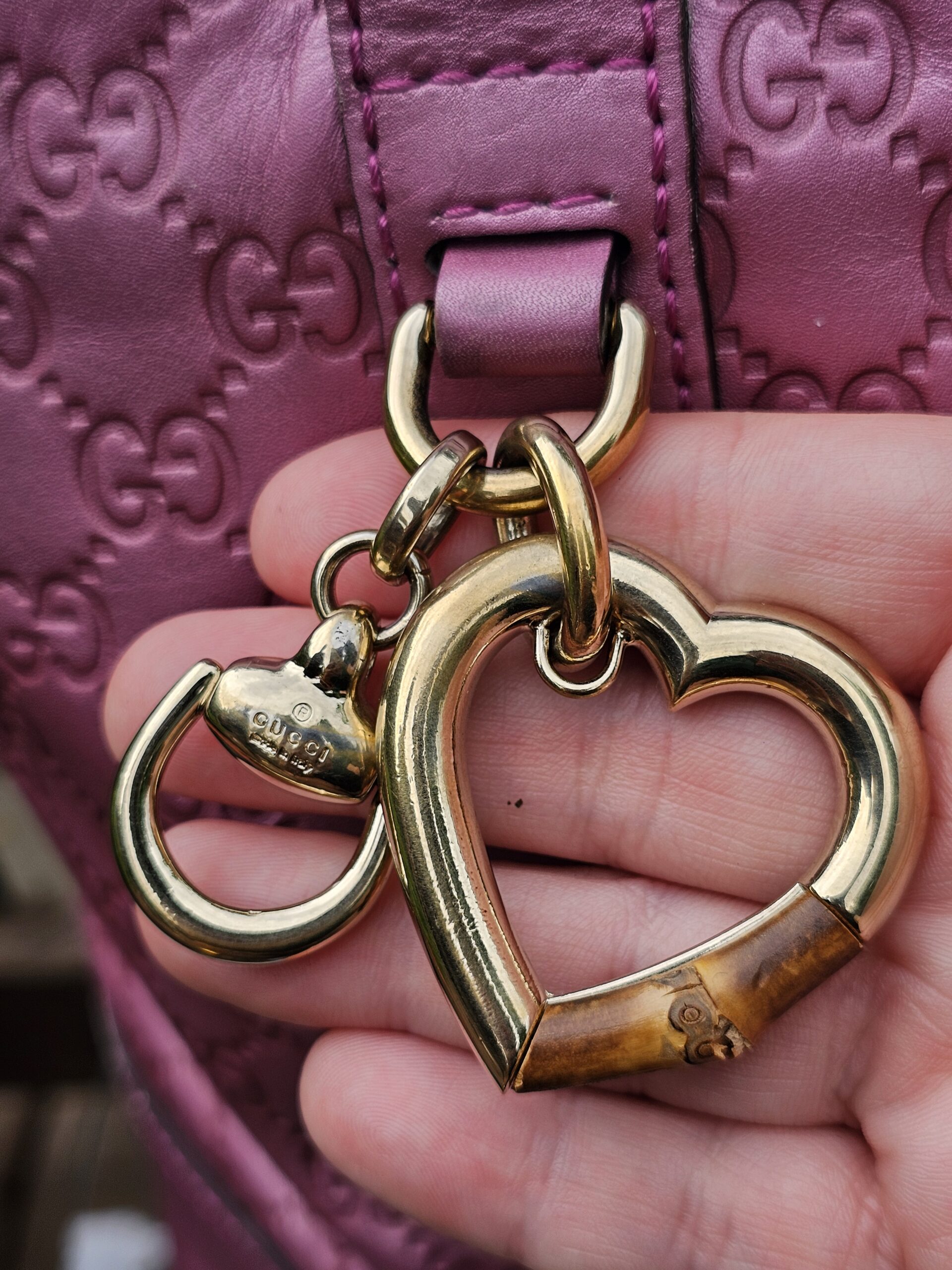 Gucci Heart Bit charm with bamboo accent held in hand, showing wear to the bamboo