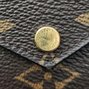 Close-up of the gold-tone Louis Vuitton engraved snap stud on the Recto Verso card holder flap