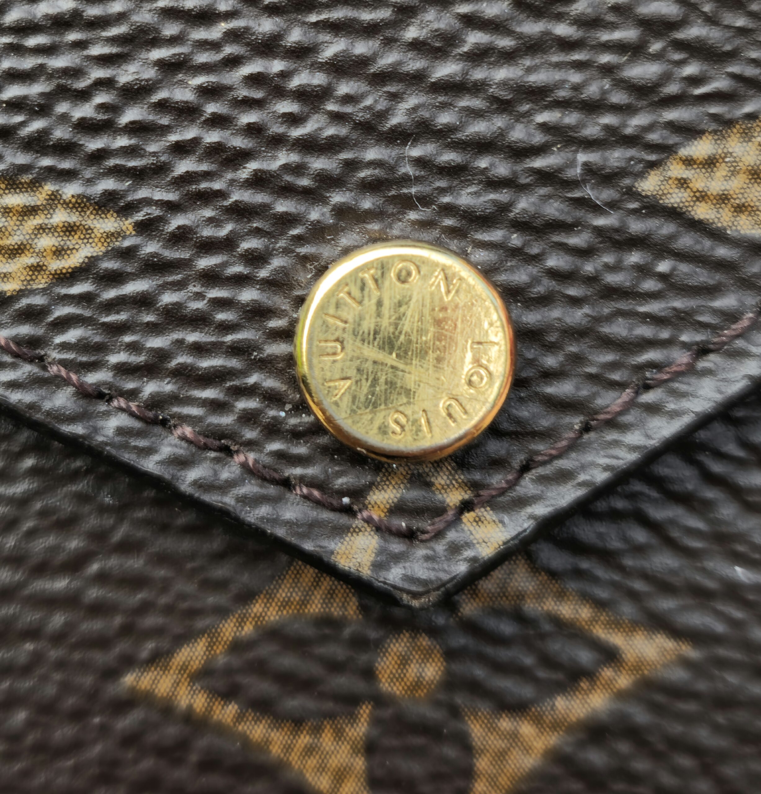 Close-up of the gold-tone Louis Vuitton engraved snap stud on the Recto Verso card holder flap