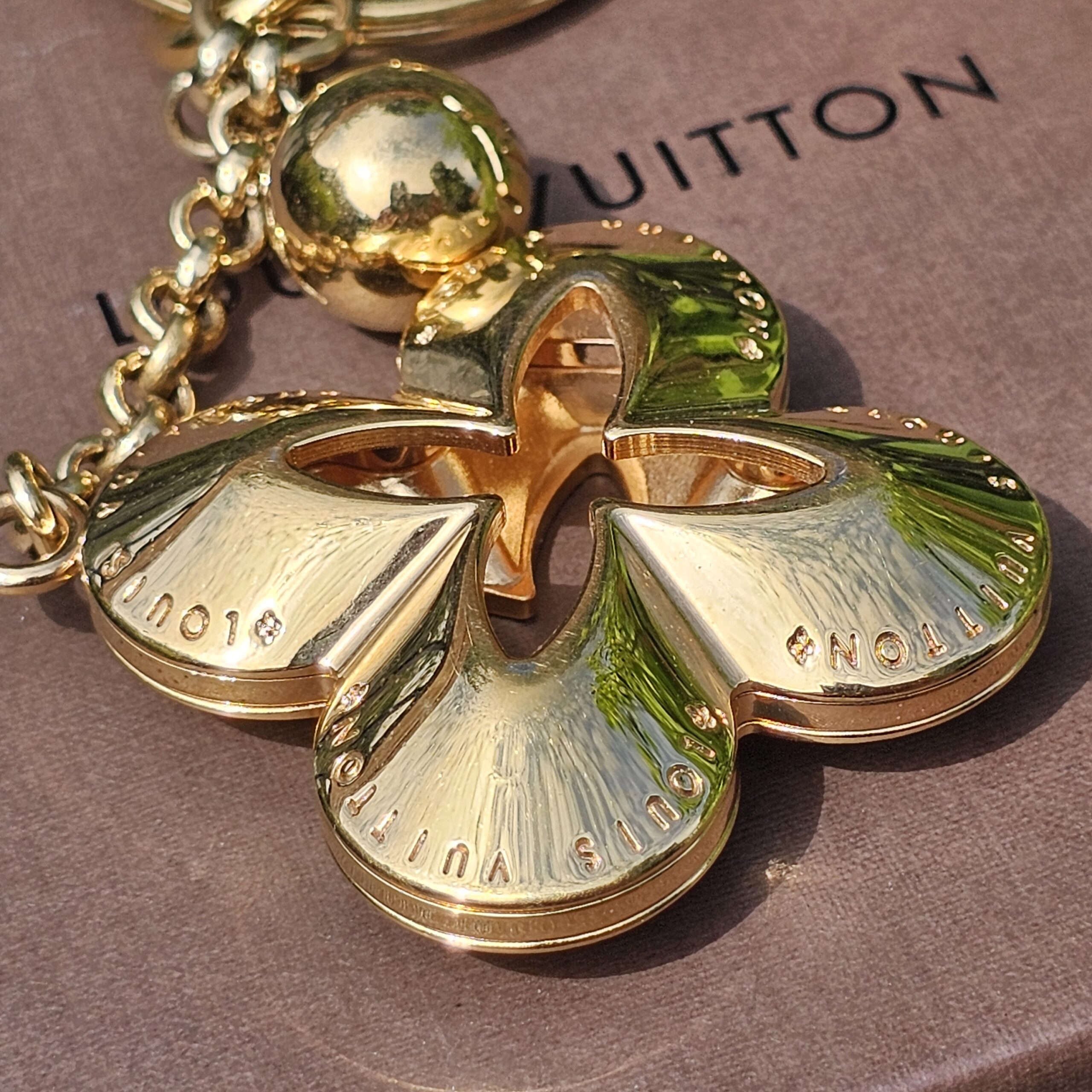 Louis Vuitton engraved across the petals of the Eclipse gold-tone flower charm