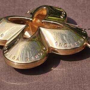 Gold-tone Monogram flower charm of the Louis Vuitton Eclipse key holder shown close up