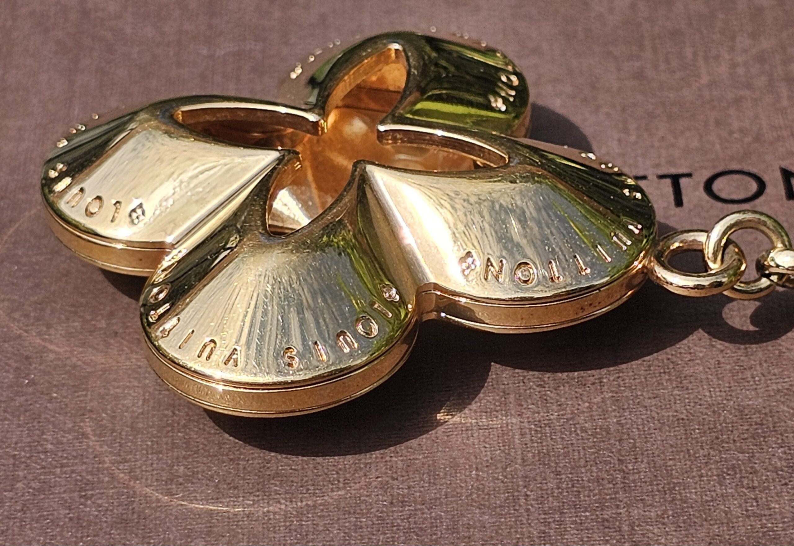 Gold-tone Monogram flower charm of the Louis Vuitton Eclipse key holder shown close up