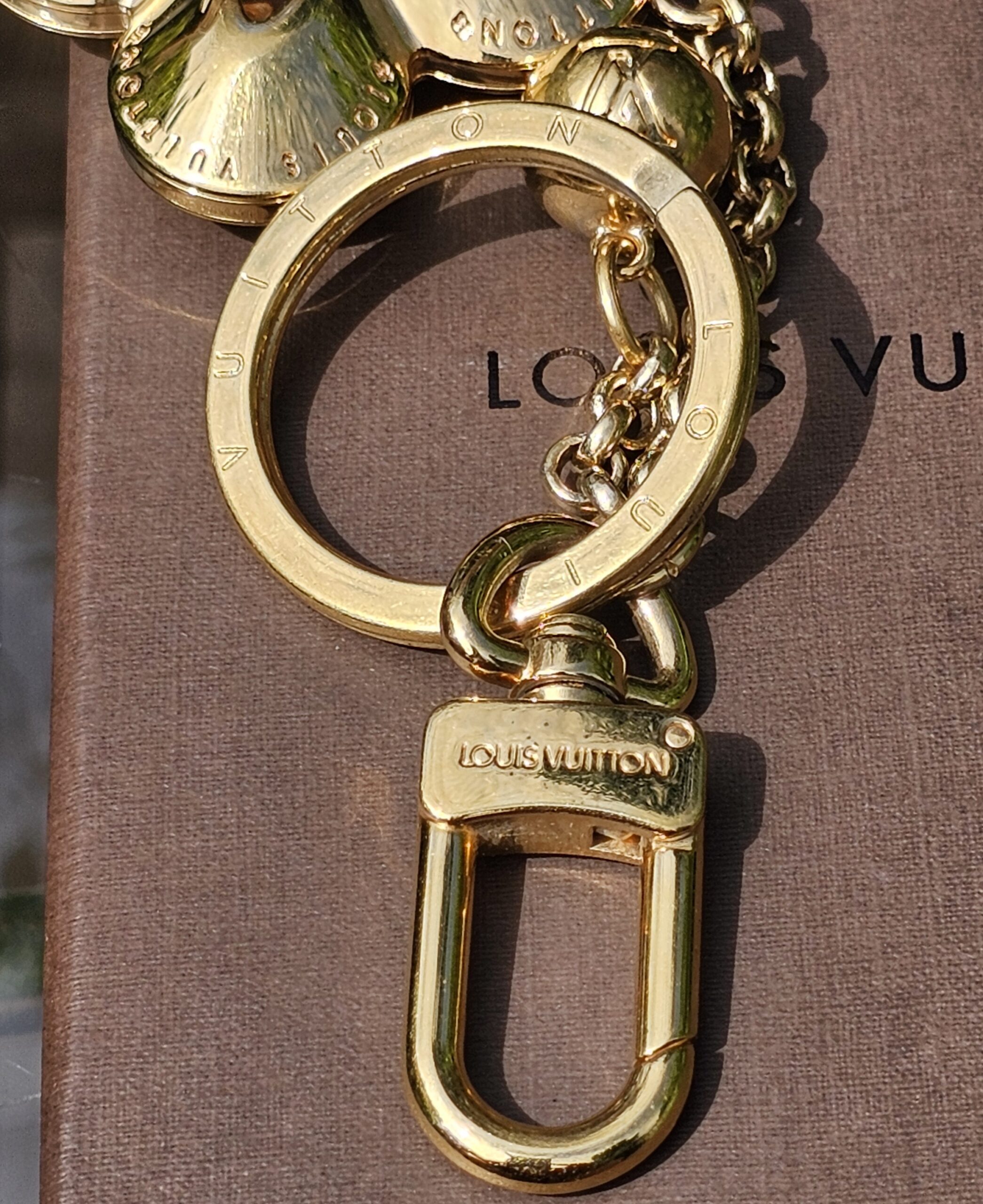 Gold-tone lobster clasp stamped Louis Vuitton on the Eclipse key holder and bag charm