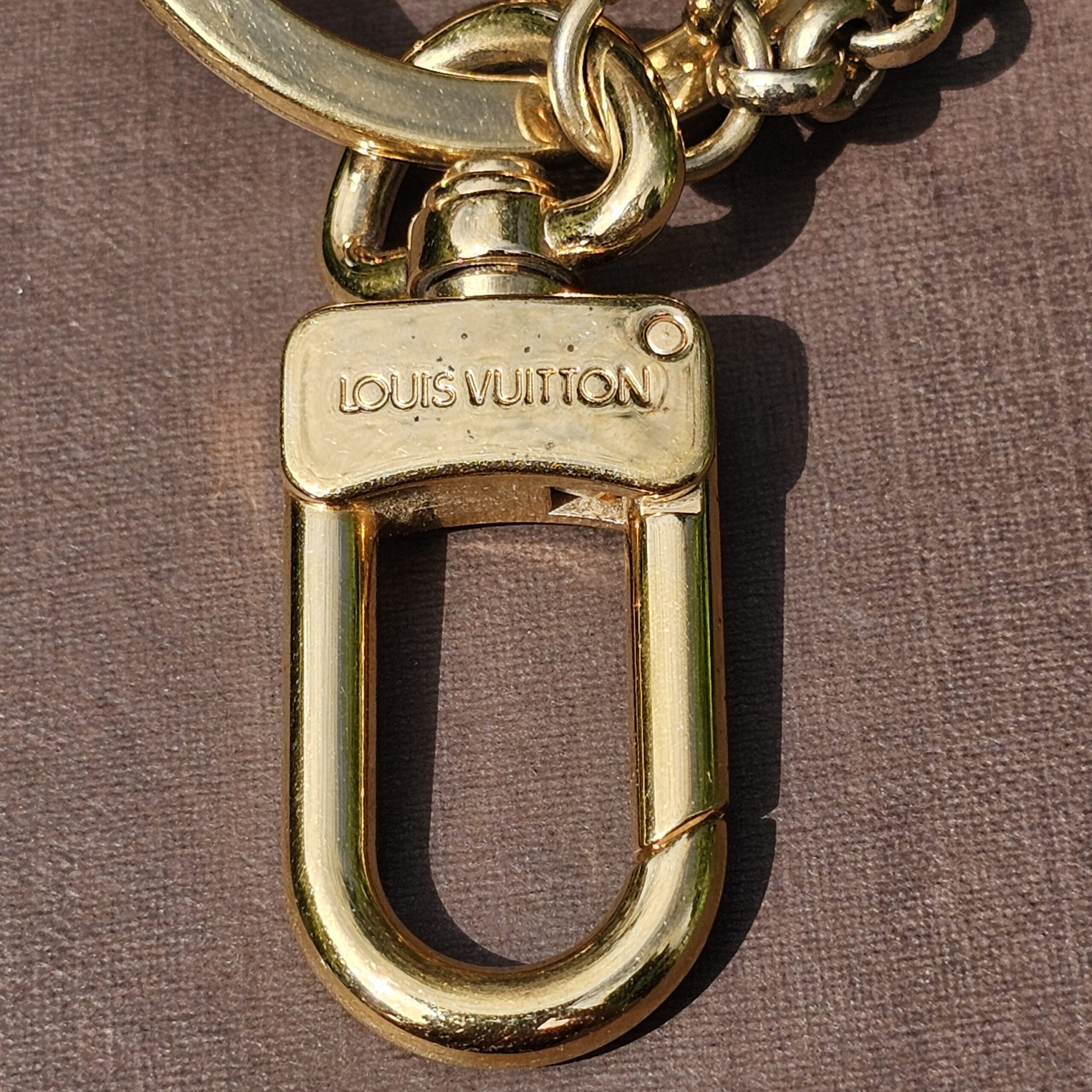 Louis Vuitton stamped on the gold-tone clasp of the Eclipse key holder and bag charm