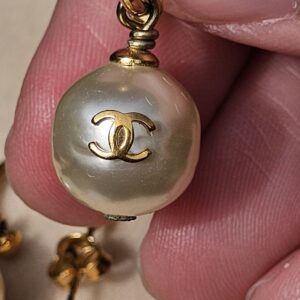 Close-up of the gold-tone CC logo set into the faux pearl of the Chanel drop earring