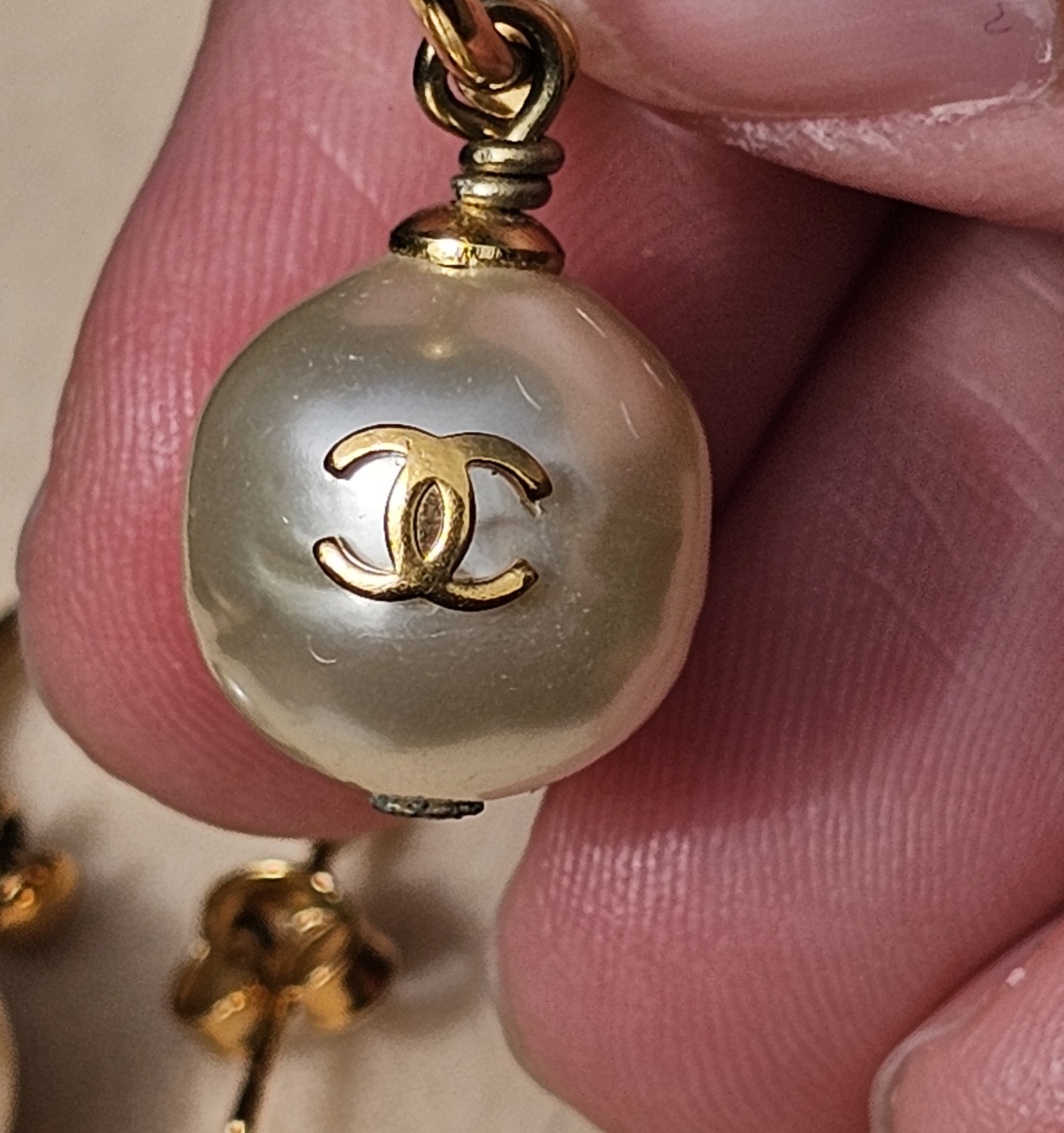 Close-up of the gold-tone CC logo set into the faux pearl of the Chanel drop earring