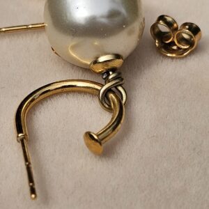 Close-up of a Chanel faux pearl drop earring showing the pearl surface and gold-tone connection