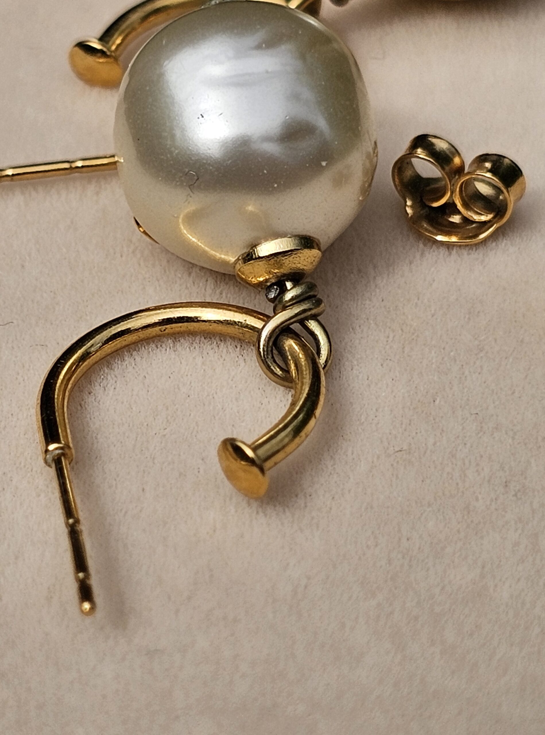 Close-up of a Chanel faux pearl drop earring showing the pearl surface and gold-tone connection