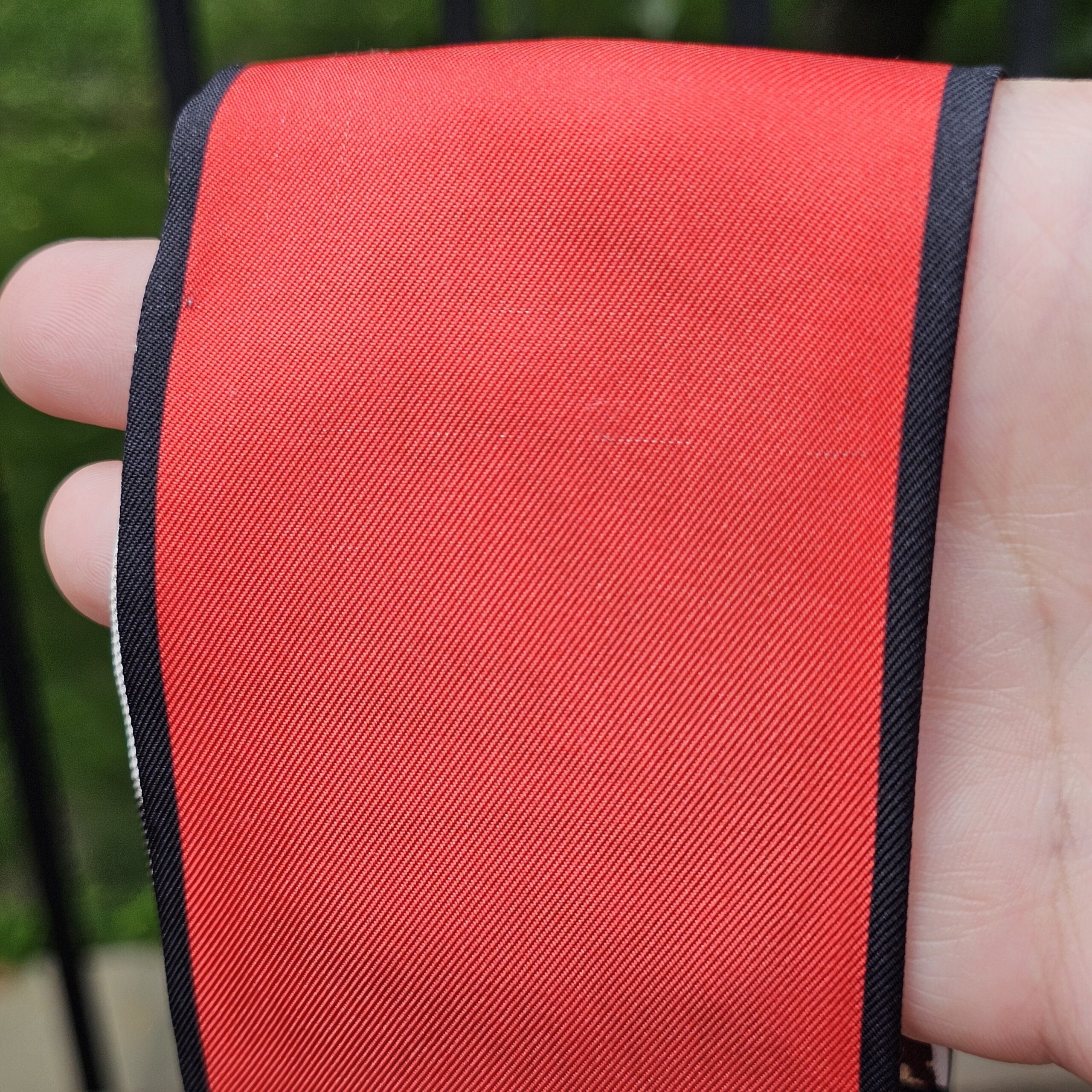 Close-up of the red silk on the Louis Vuitton Trunks bandeau held in hand