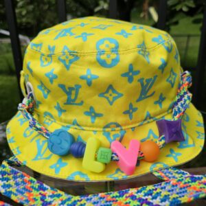 Front of the Louis Vuitton Virgil Abloh bucket hat showing the blue Monogram print on yellow cotton and the beaded cord