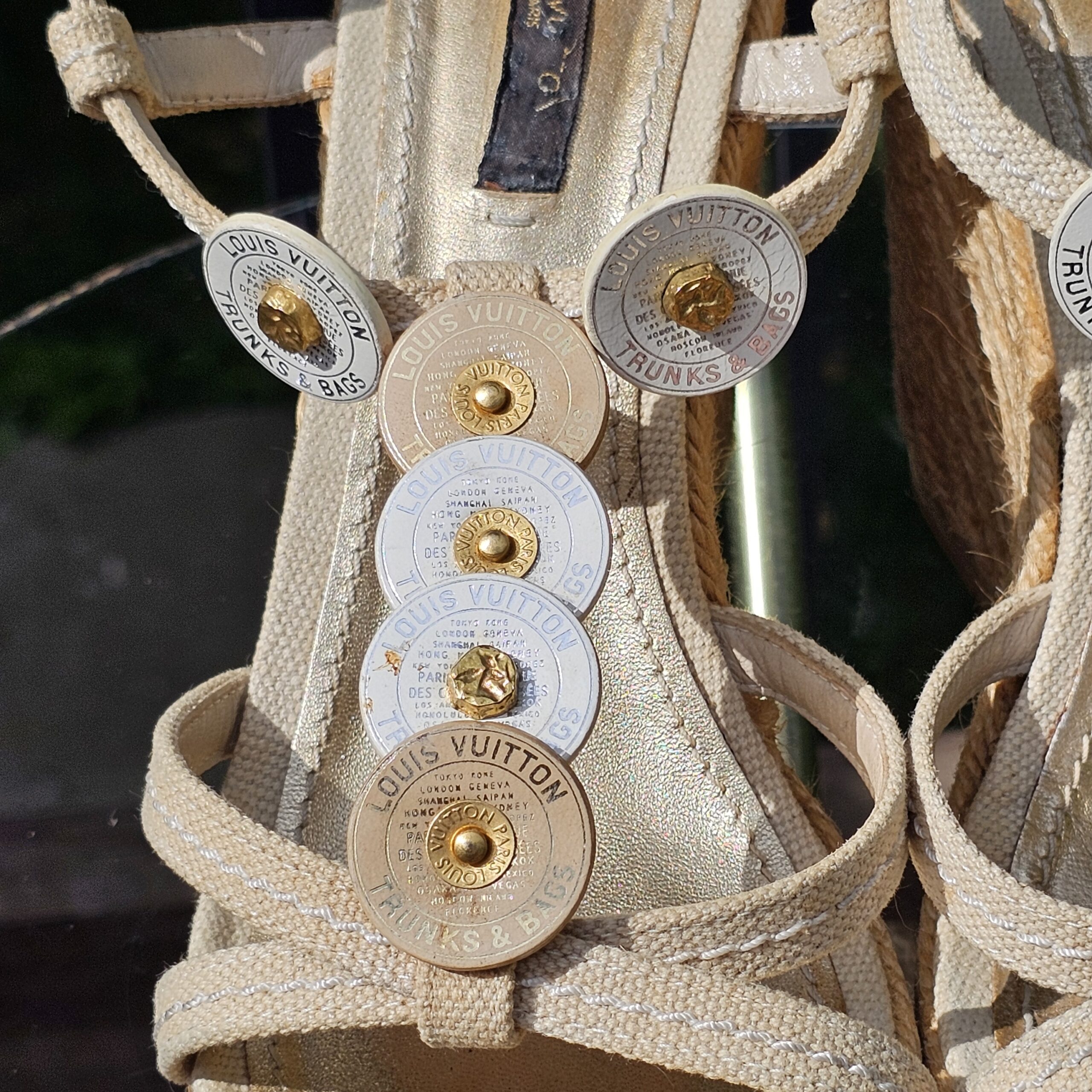 Close-up of the Trunks and Bags discs and gold-tone studs on the Louis Vuitton espadrille wedge sandal straps