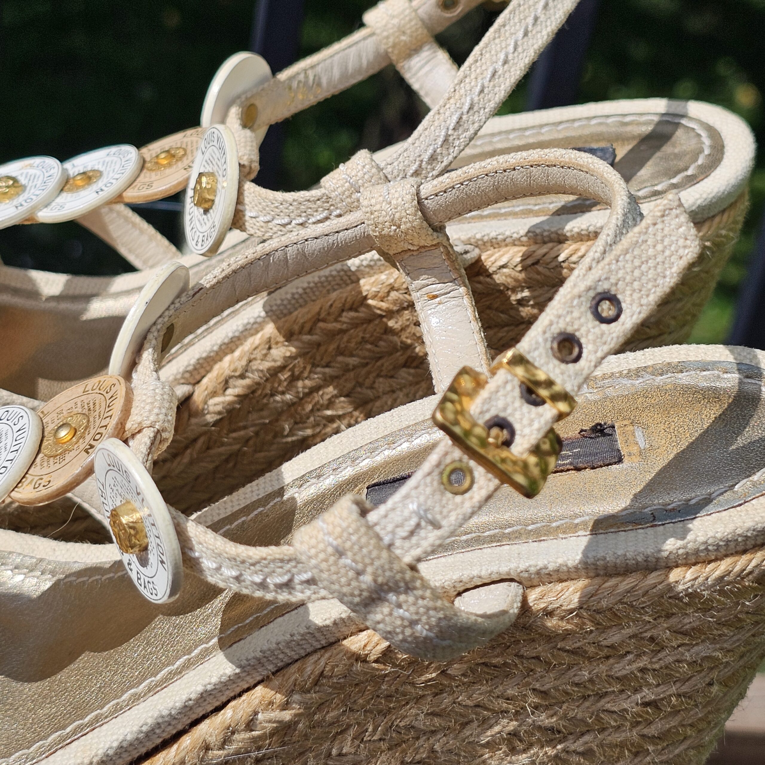Cream canvas straps and gold-tone buckle on the Louis Vuitton espadrille wedge sandals showing wear near the buckle