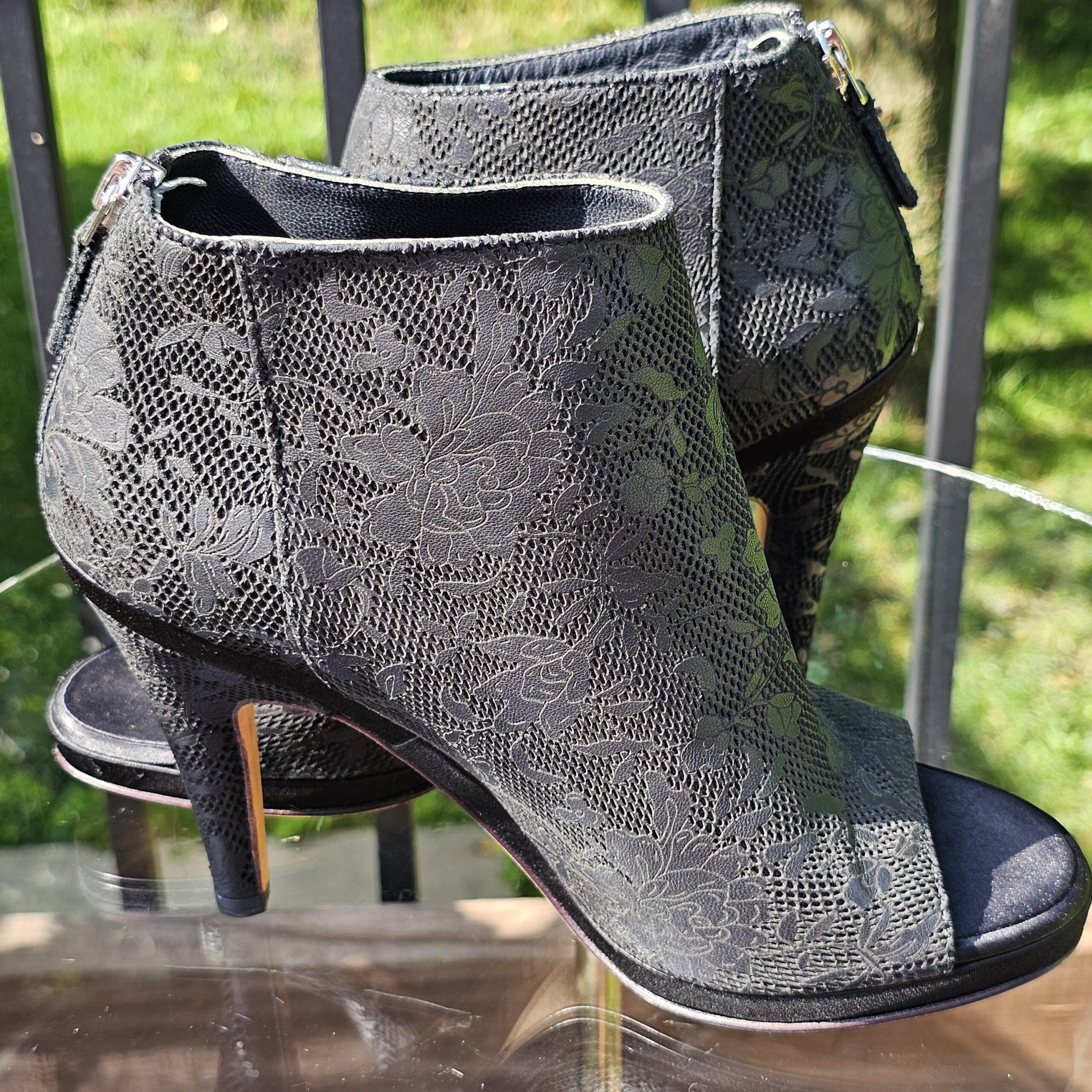Pair of Chanel peep toe ankle booties shown from the side with the lace pattern visible