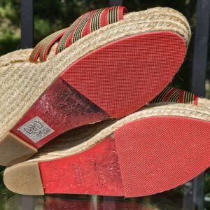Signature red soles of the Christian Louboutin espadrille wedge sandals showing wear from use