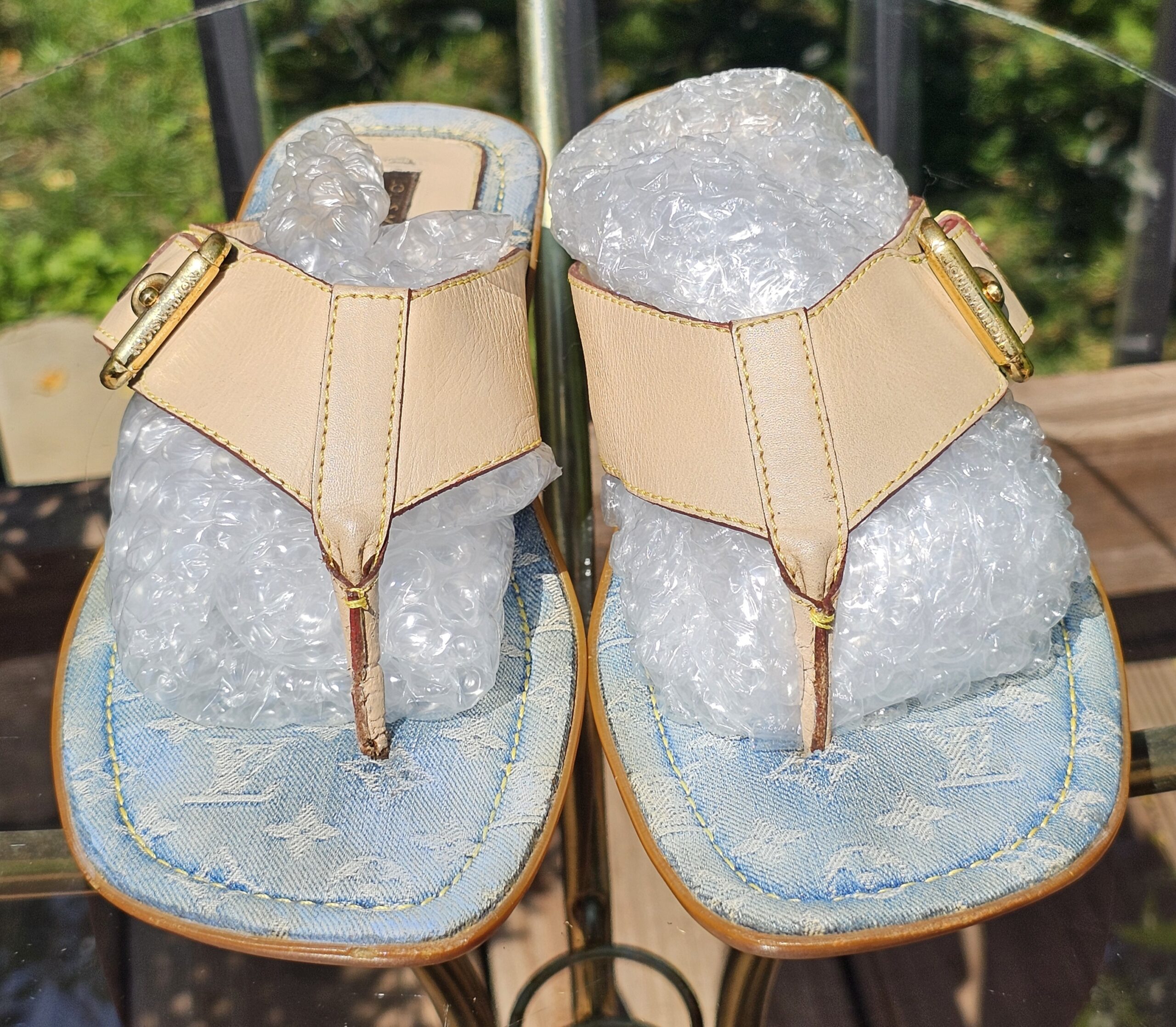Top view of both Louis Vuitton Monogram denim thong sandals showing the leather T-straps and gold-tone hardware