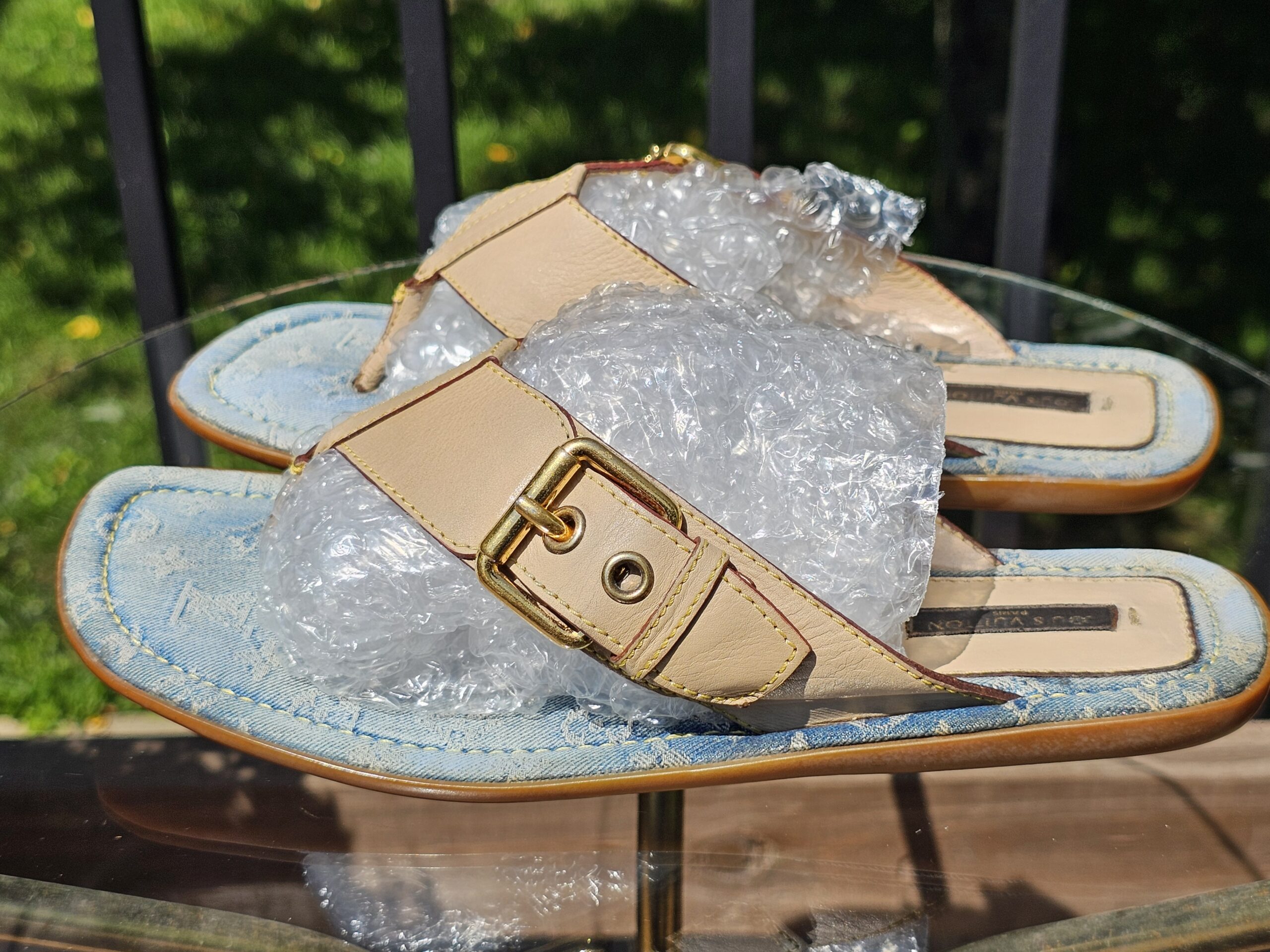 Natural leather T-straps and gold-tone buckles on the Louis Vuitton Monogram denim thong sandals