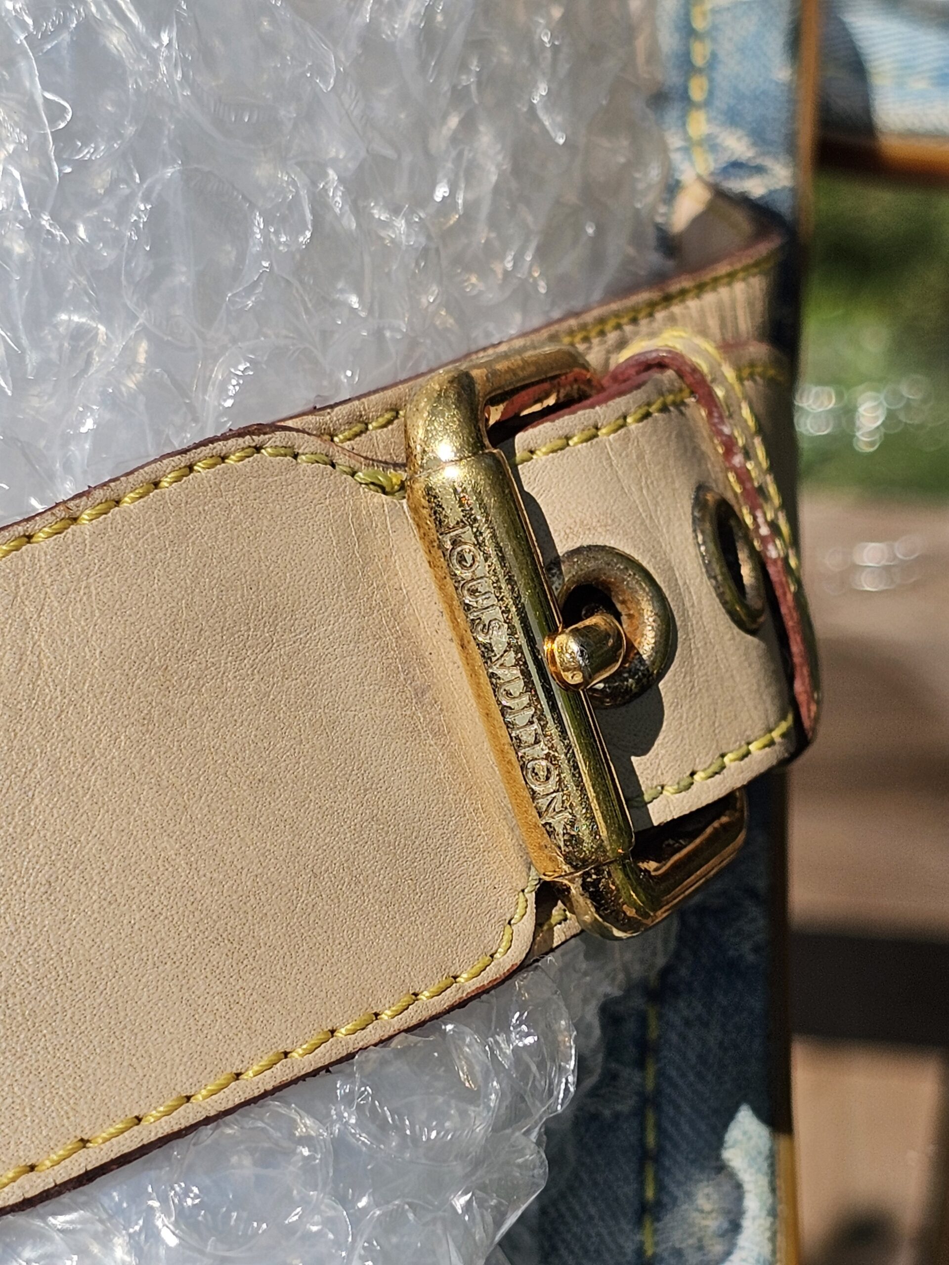 Close-up of the gold-tone buckle hardware on the Louis Vuitton Monogram denim thong sandals showing surface wear