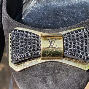 Crystal embellished bow with gold-tone LV plaque on the toe of the Louis Vuitton suede pumps