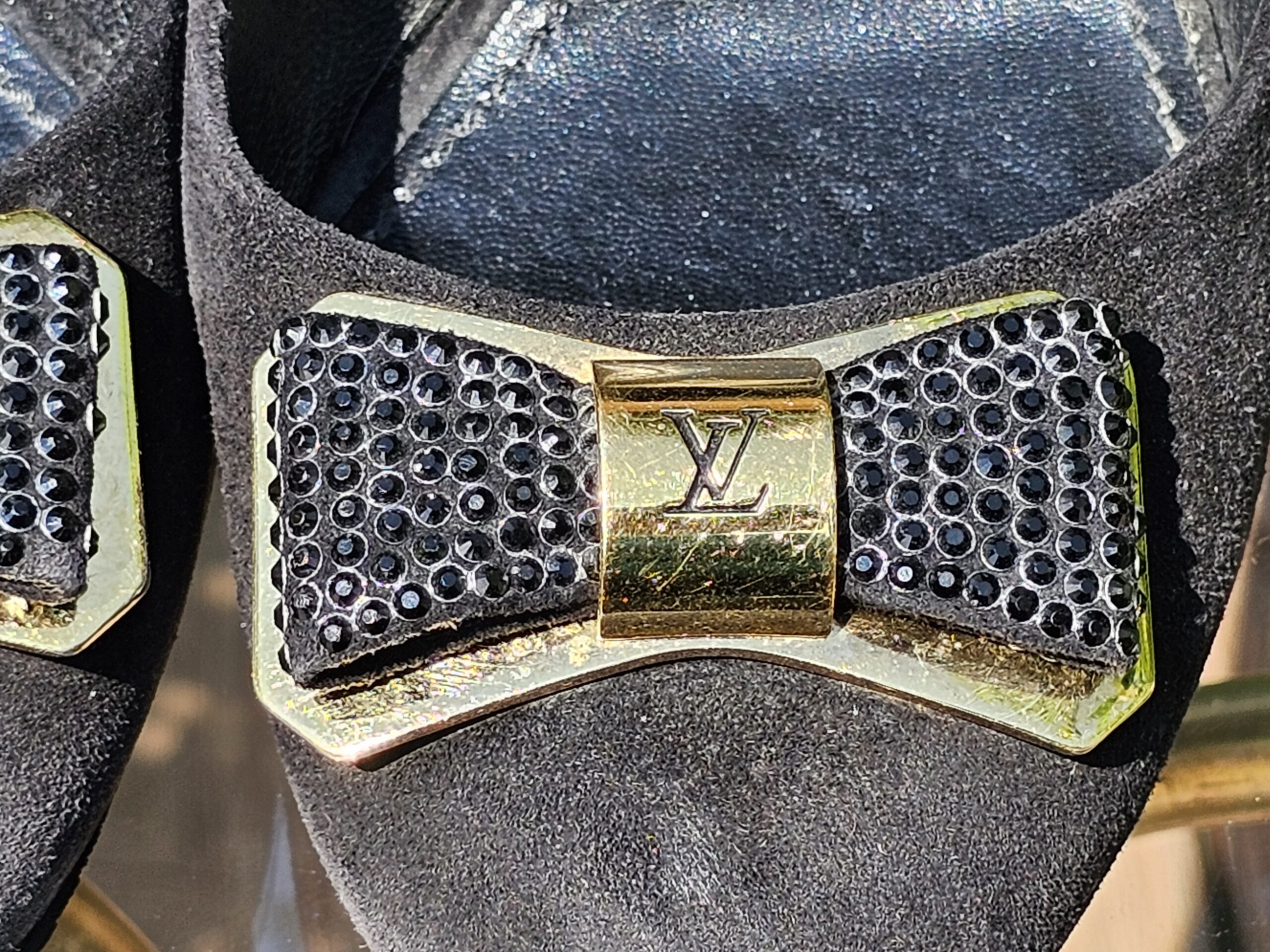 Crystal embellished bow with gold-tone LV plaque on the toe of the Louis Vuitton suede pumps