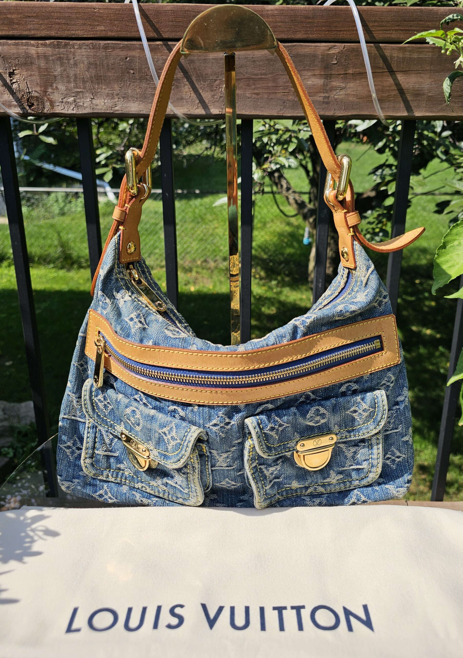 Louis Vuitton Baggy PM in blue Monogram denim shown hanging by its vachetta strap above the Louis Vuitton dust bag