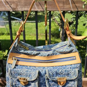 Front view of the Louis Vuitton Monogram Denim Baggy PM showing the exterior zip pocket and two flap pockets with gold-tone hardware