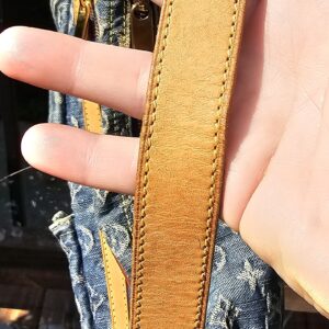 Vachetta strap of the Louis Vuitton Monogram Denim Baggy PM held in hand showing warm patina and light wear