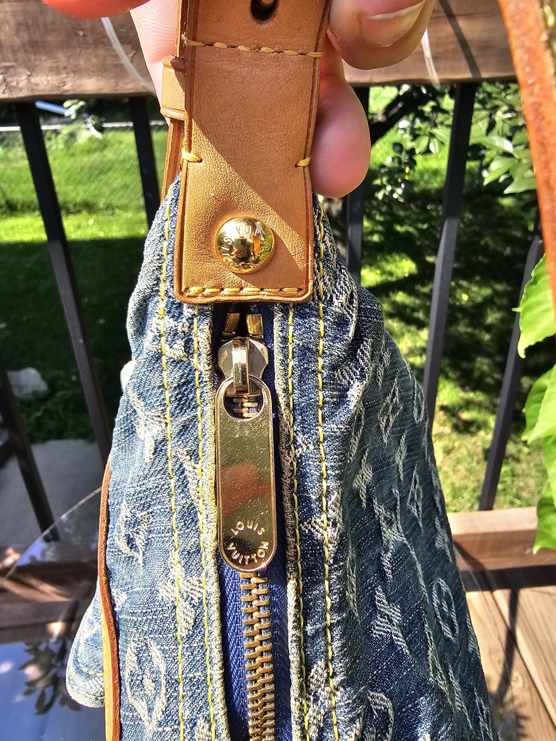 Vachetta leather tab and gold-tone hardware attaching the strap to the Louis Vuitton Monogram Denim Baggy PM