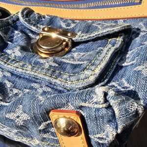 Gold-tone stud closure on a front flap pocket of the Louis Vuitton Monogram Denim Baggy PM