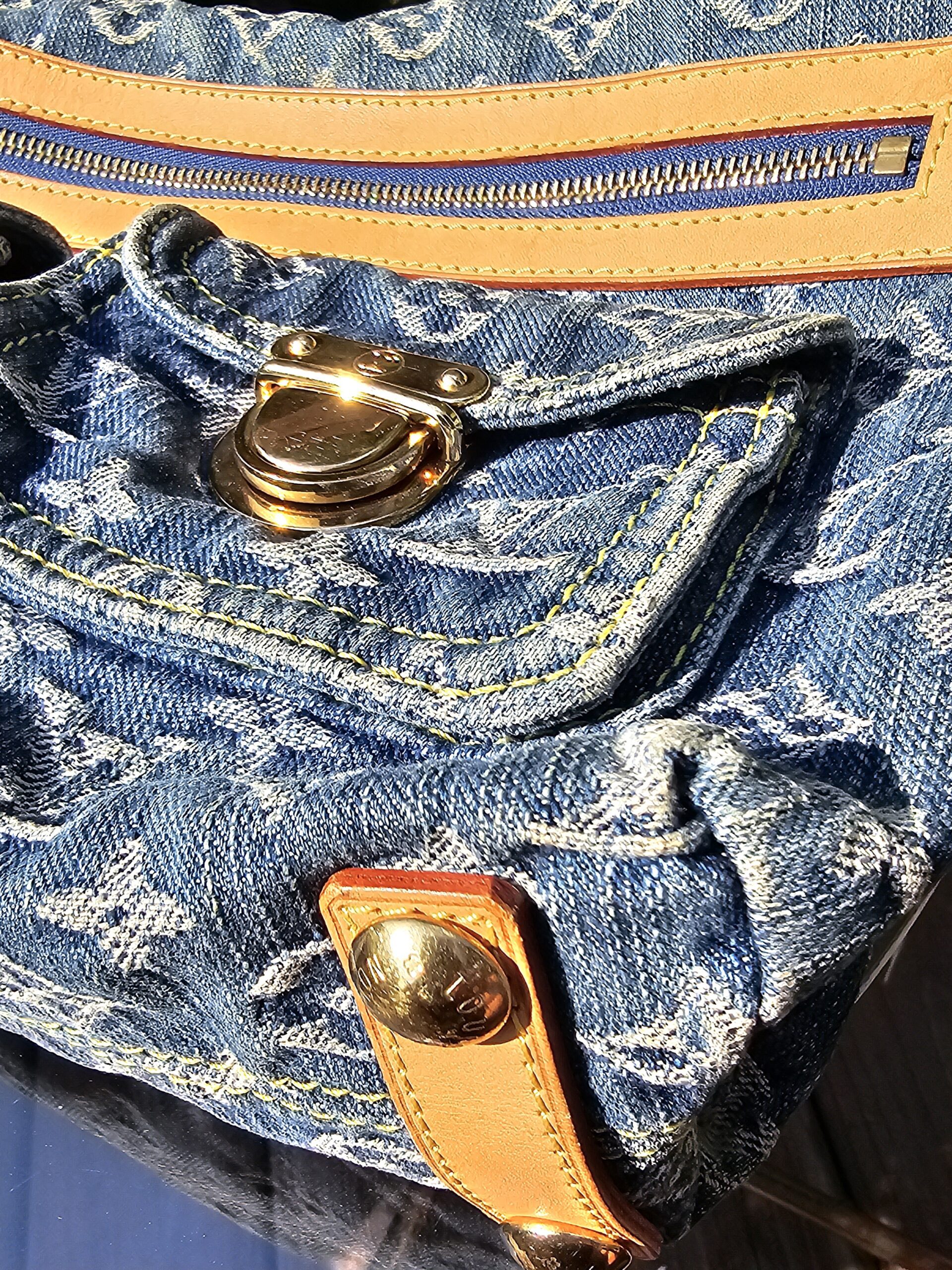 Gold-tone stud closure on a front flap pocket of the Louis Vuitton Monogram Denim Baggy PM
