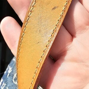 Underside of the vachetta strap on the Louis Vuitton Monogram Denim Baggy PM showing marks from previous use