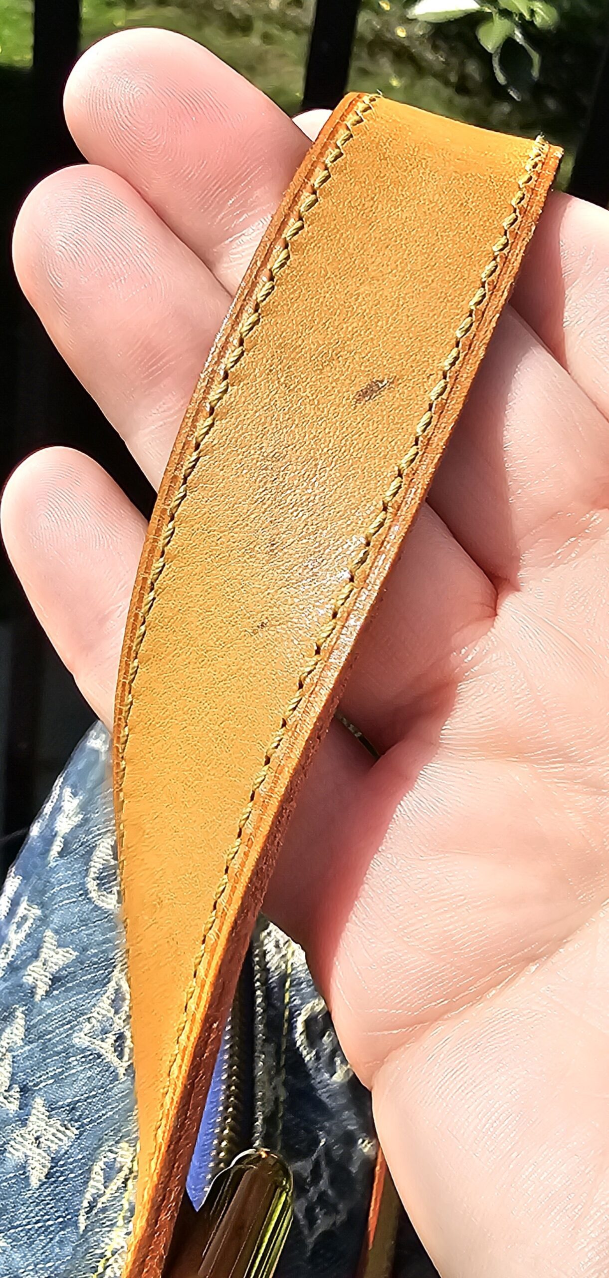 Underside of the vachetta strap on the Louis Vuitton Monogram Denim Baggy PM showing marks from previous use