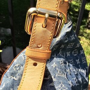 Close-up of the gold-tone strap buckle and vachetta punch holes on the Louis Vuitton Monogram Denim Baggy PM