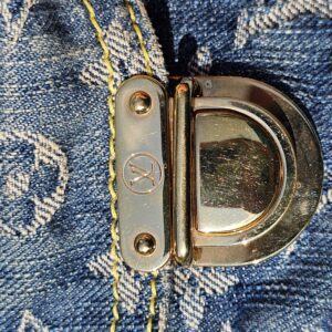 Gold-tone turnlock hardware on the front of the Louis Vuitton Monogram Denim Baggy PM