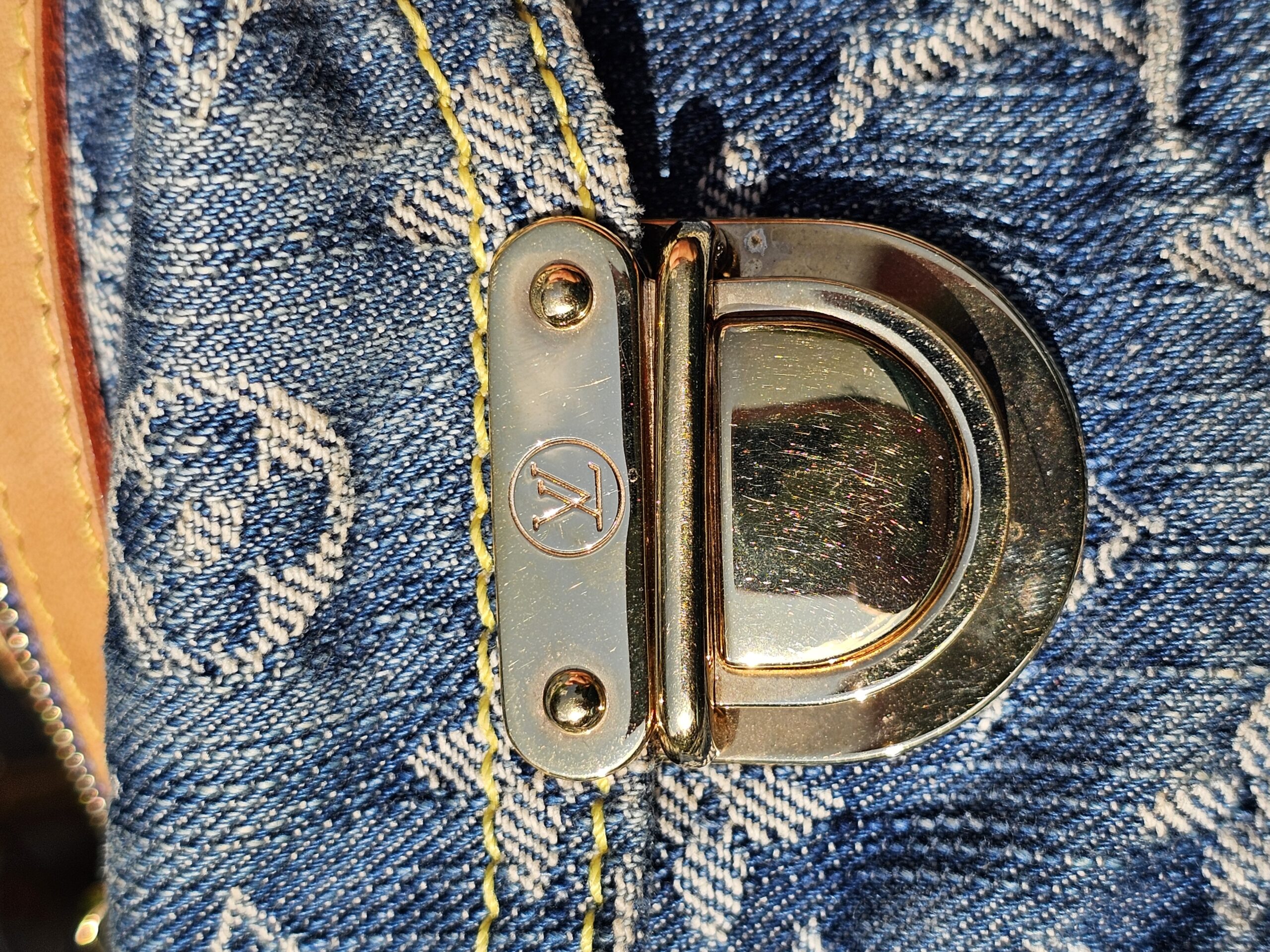 Gold-tone turnlock hardware on the front of the Louis Vuitton Monogram Denim Baggy PM