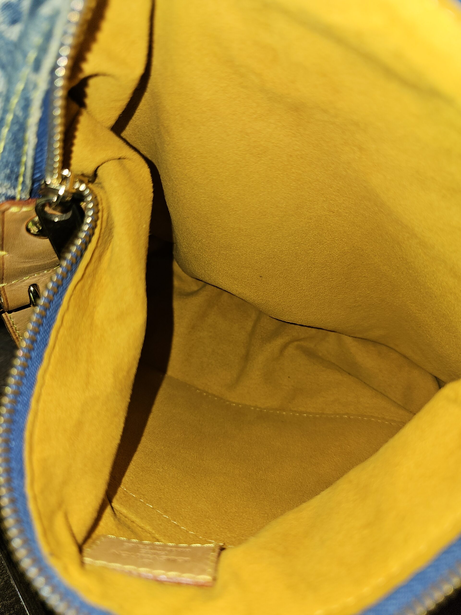 Interior slip pocket of the Louis Vuitton Monogram Denim Baggy PM in yellow lining