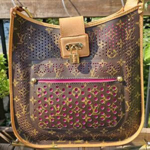 Front of the Louis Vuitton Monogram Perforated Musette showing bright pink showing through the perforated Monogram canvas and the front pocket
