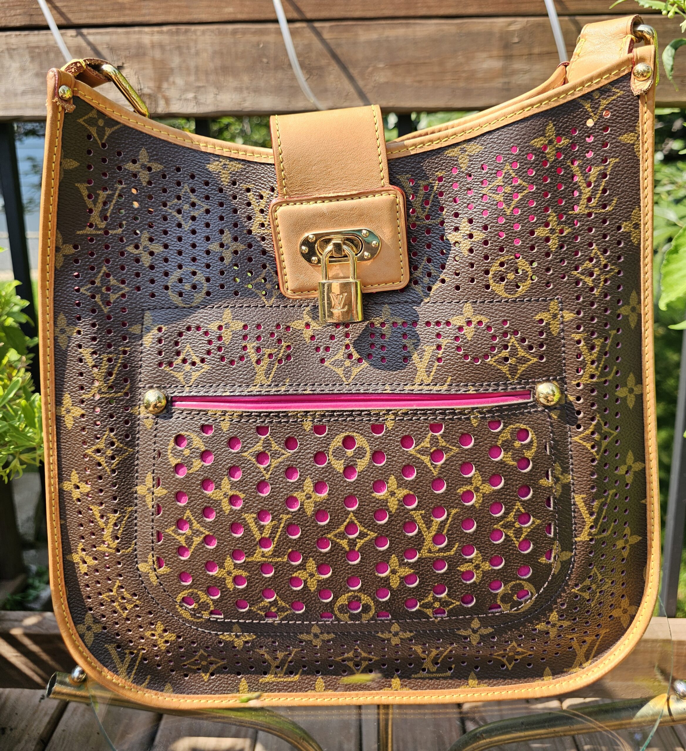 Front of the Louis Vuitton Monogram Perforated Musette showing bright pink showing through the perforated Monogram canvas and the front pocket