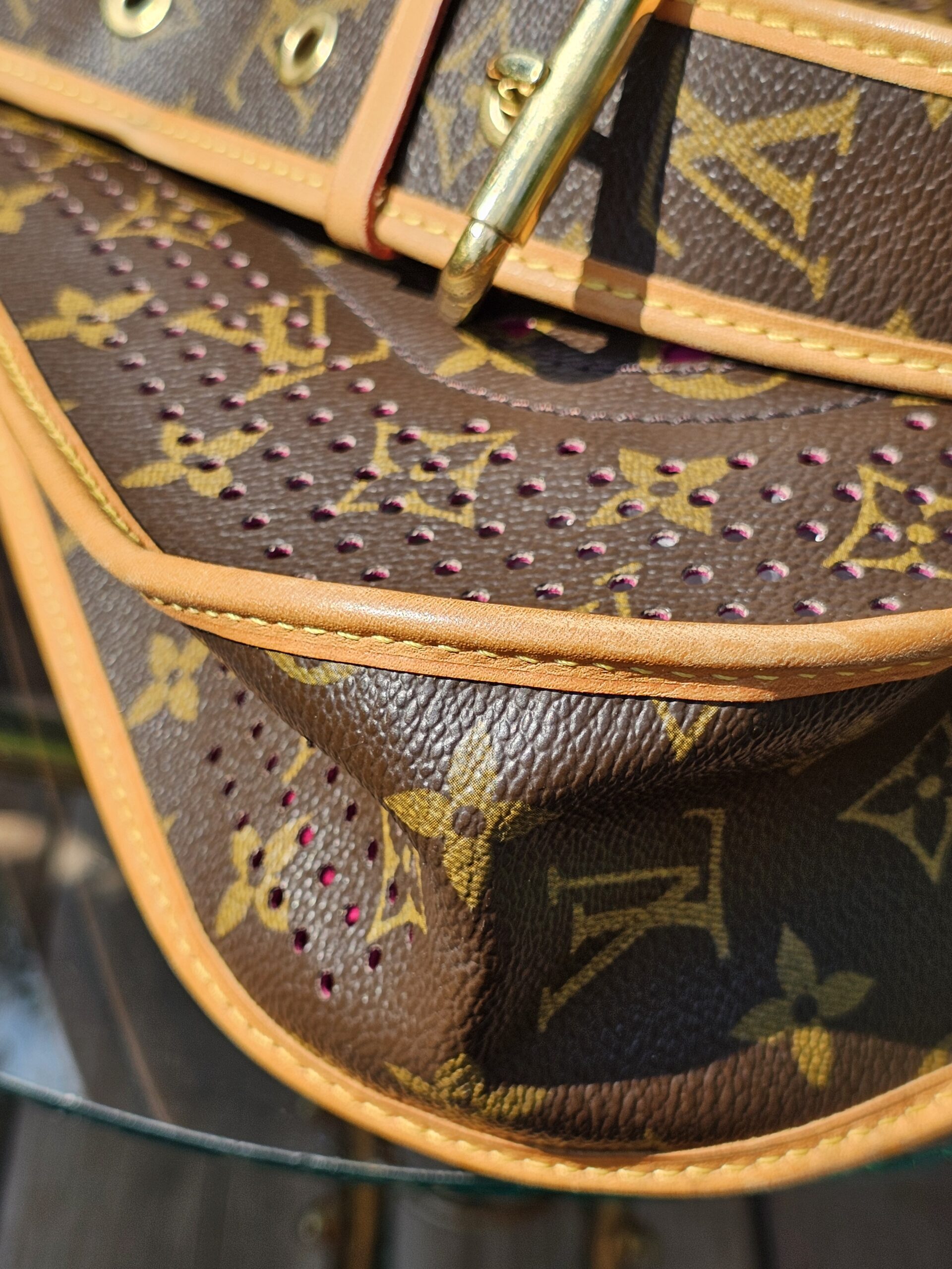 Side of the Louis Vuitton Monogram Perforated Musette showing the perforated panel meeting the vachetta trim