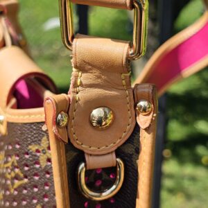 Gold-tone ring and vachetta tab where the strap attaches to the Louis Vuitton Monogram Perforated Musette